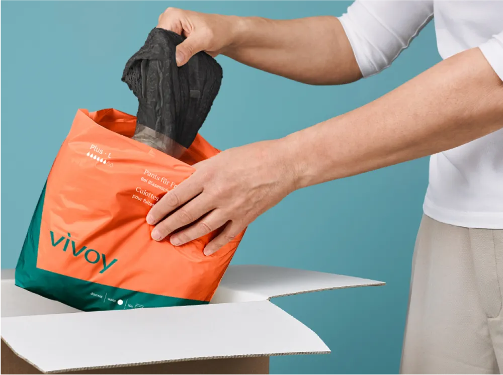 Dezente Pants von vivoy Jemand packt eine schwarze Pants aus einer vovoy Verpackung aus.